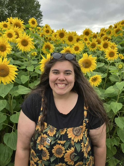 Image of Dr Laura Bower standing in front of a sunflower field. 