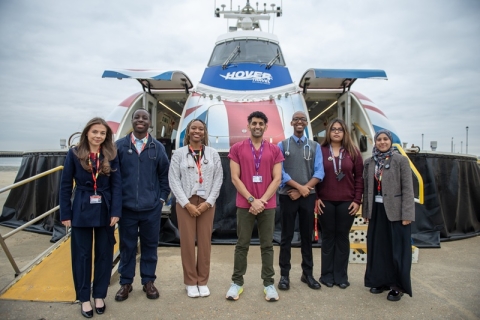Medical degree students stand in front of the Hovertravel hovercraft smiling