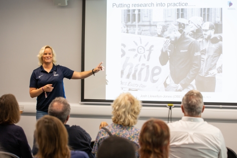 Academic stood at front of the class with a powerpoint