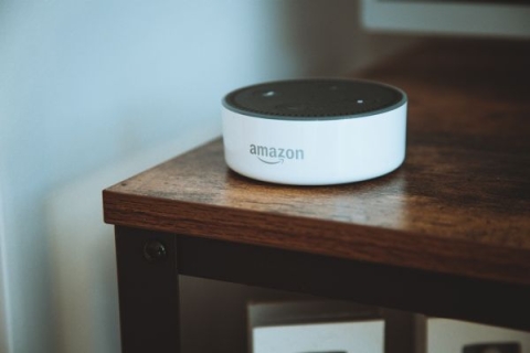 A white Amazon Alexa on top of a brown wooden table
