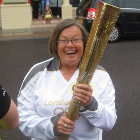 Image of Bronwin Carter holding the olympic flame smiling to camera