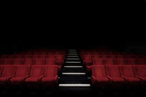 An empty cinema screening room with rows and rows of red seats