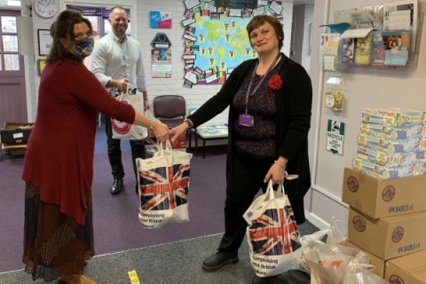 woman handing over bag of donations to another woman