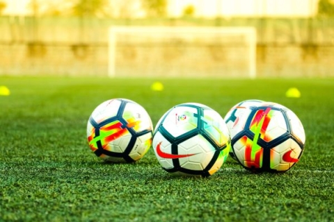 Three footballs on a football pitch