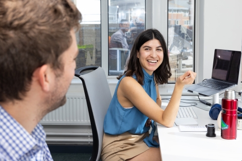 Woman in office environment smiling with colleague