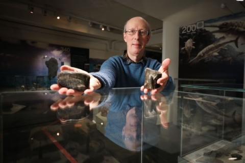 Man holding two fossils in each hand.