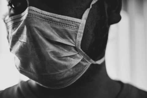 black and white photo of a man wearing a surgical mask