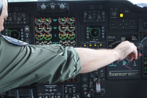 The military man is holding his hand on the control panel