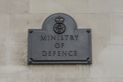 A picture of a grey sign on a building saying the words 'Ministry of Defence' 