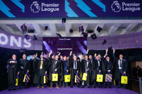 Premier Leagues coaching graduates throwing graduation caps in the air