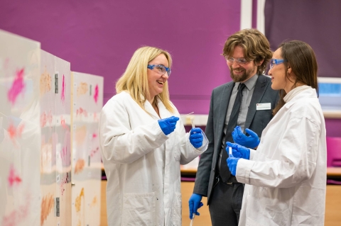 Three people in lab robes chatting