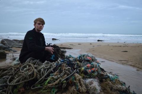 individual sitting next to a heap of plastic waste near the seashore