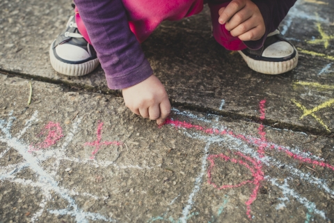 Child drawing with chalk on pavement