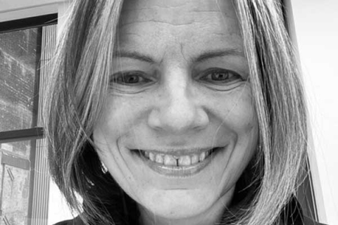 A black and white picture of alumna, Sarah Caddick smiling to camera