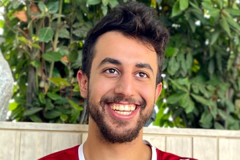 Graduate Tameem Alrababah smiling at camera with greenery backdrop