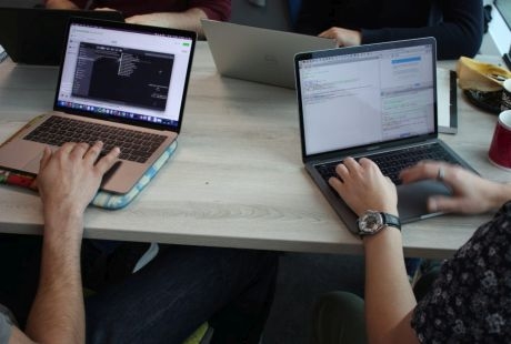 Two people sat at a table using laptops