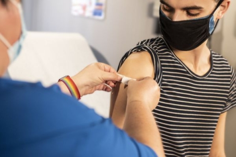 A nurse putting a plaster on someone's arm after they have received the covid vaccination