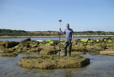 Academic stood on some rocks in shallow water
