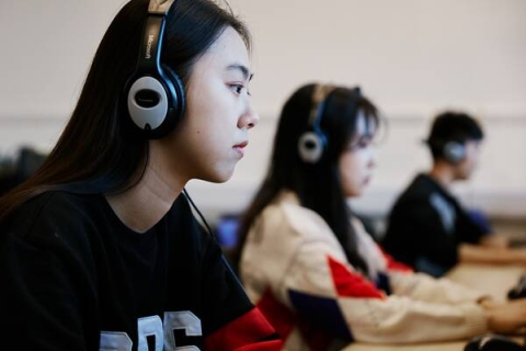 three students in a row wearing headphones