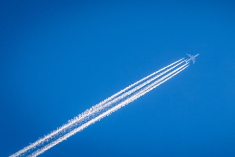 A jet against a blue sky with contrail