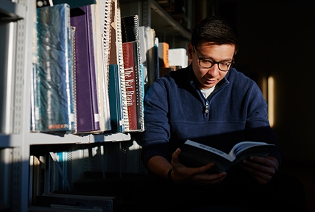 Male student reading in library