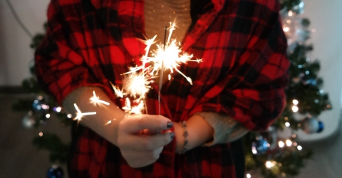 Person wearing red and black shirt holding a sparkler
