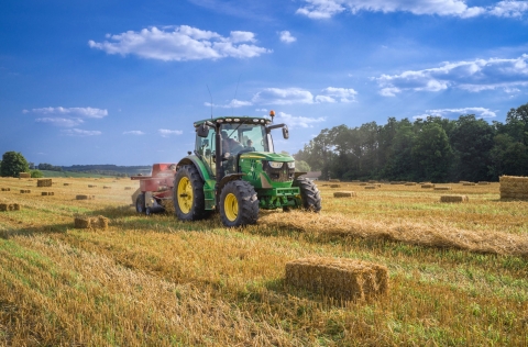 Green tractor in a field baling hay