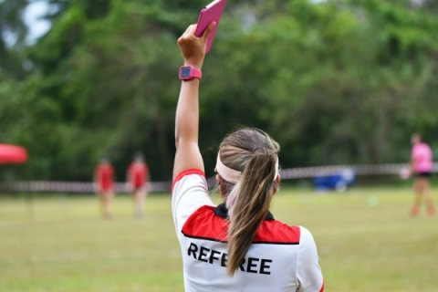Back view of female referee holding up a card