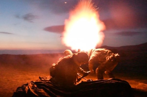 Two soldiers firing a rocket in the desert at nighttime.