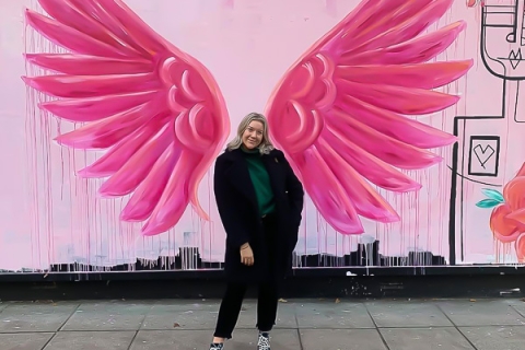 Sam Watkins standing in front of a wall with pink wings painted on it