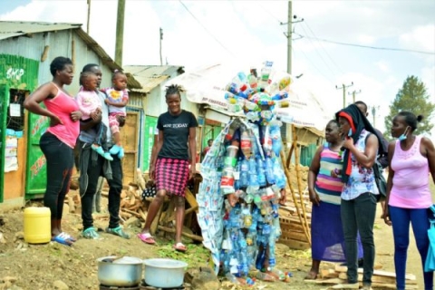 People in Africa around a 'trash-monster' made of plastic waste