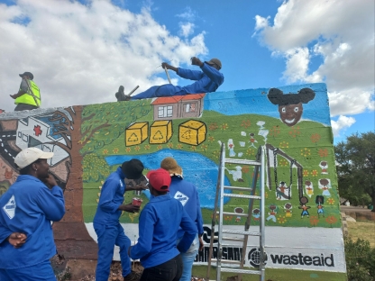 A group of people taking part in painting a brightly coloured mural