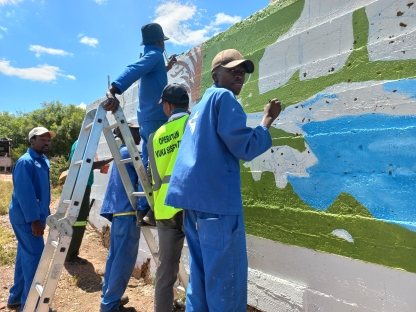 The mural being completed by people wearing vivid blue outfits