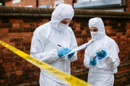 Two students in hazmat suits take notes at crime scene