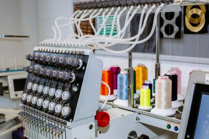 An industrial sewing machine and spools of thread
