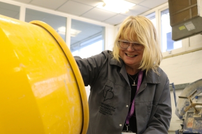 A woman with glasses using cement mixer