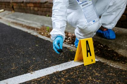 Student in biohazard suit kneels at crime scene