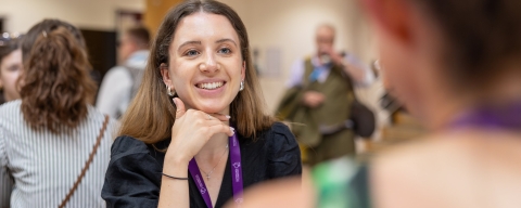 A person smiles while in conversation with another person at an event