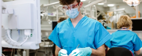 Dental hygiene student in blue scrubs working on a phantom head