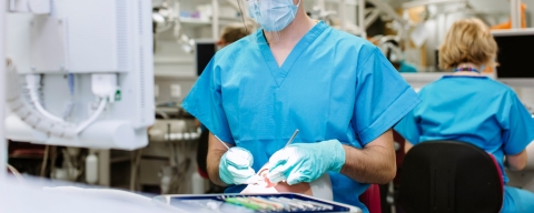 Dental hygiene student in blue scrubs working on a phantom head