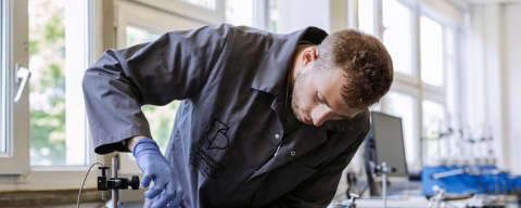 Student leaning over working on a machine in a robotics lab 
