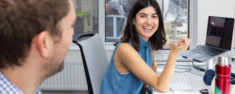 Woman in office environment smiling with colleague