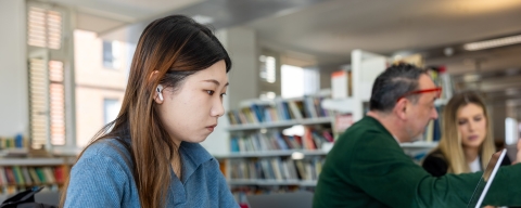 Female student with long hair in the library on a computer