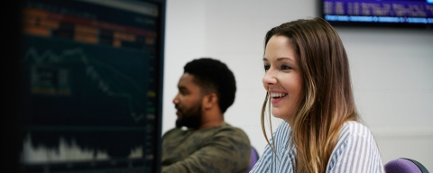 Woman smiling at computer using financial technology.