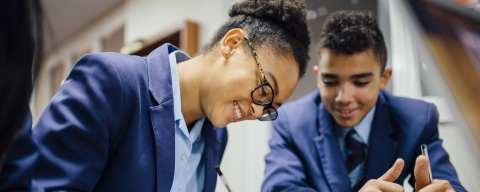 Two students smiling as they work together at a desk