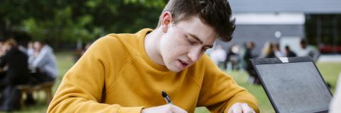 Student studying outside in yellow jumper