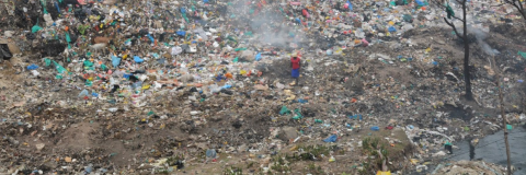 People manually sorting through a large heap of waste