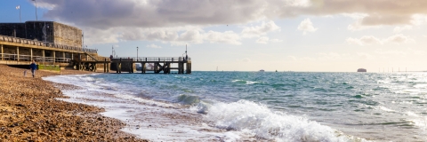 Person walking along the shore of a Portsmouth beach