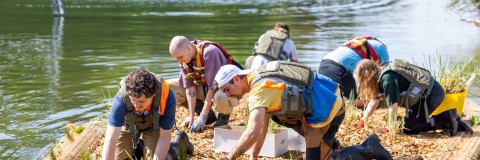 Male students on a raft studying a wetlands area - on their hands and knees scouraging through mudplains