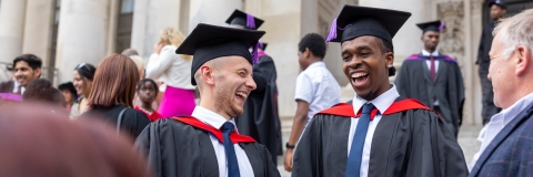 Two students laughing together on graduation day outside Portsmouth Guildhall